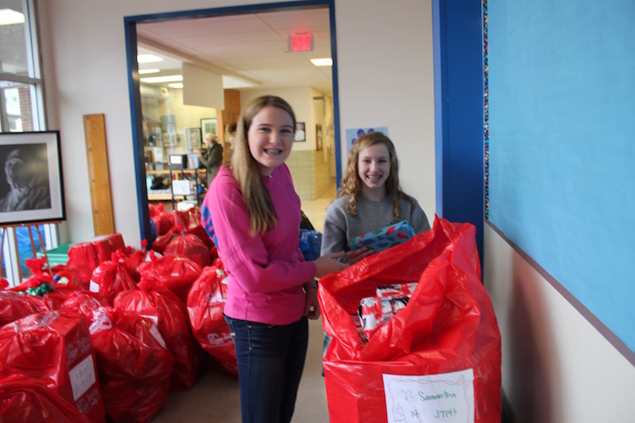 Savannah Bittner (left) and Matia Ianni, both eighth graders, load a Red Bag stuffed with gifts.