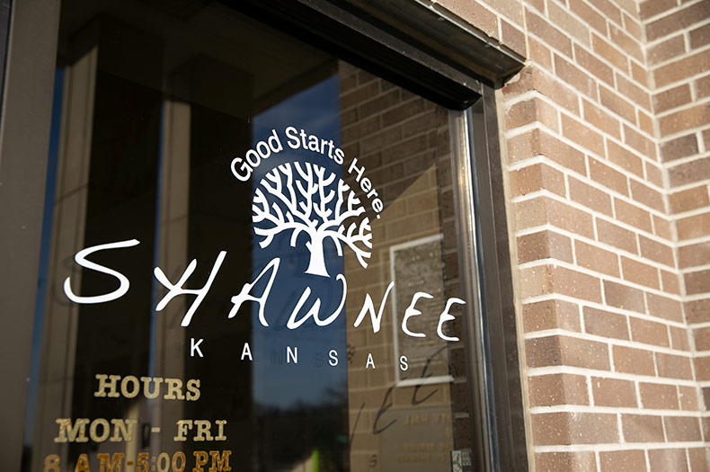 The door of Shawnee city hall has the city logo on it as well as its business hours. It's home to the city council chambers, city manager's office and several city departments.