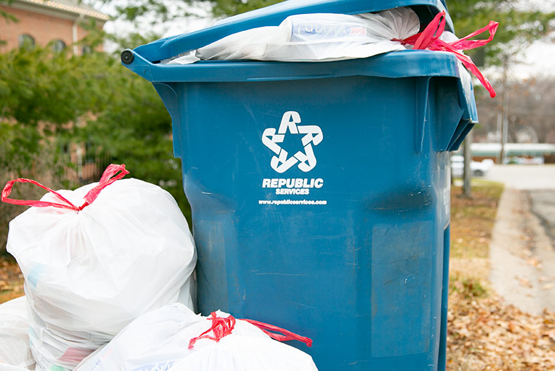 A Republic Services trash bin in Prairie Village overflows with several bags sitting next to the bin.