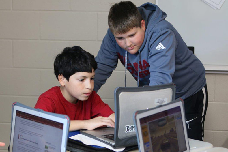 Monticello Trails Middle School students collaborate on a project in a Pathways course using laptops.