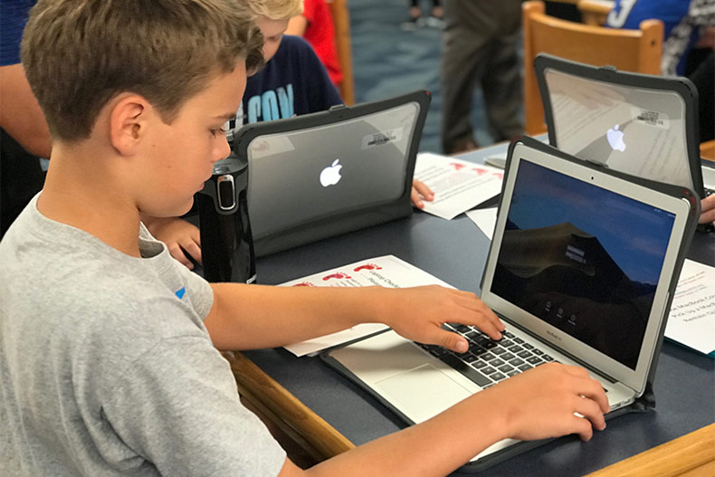 USD 232 device refresh. A middle schooler logs into his laptop.