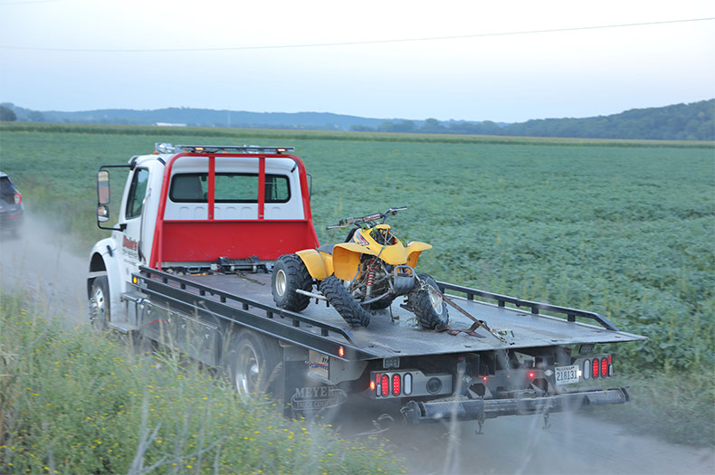 A Shawnee Police vehicle and a tow truck removing the crashed 4-wheeler.