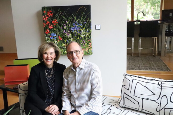 Julie and Hal Hanson in their Overland Park home with one of their late son Jeff's paintings on the wall behind them.