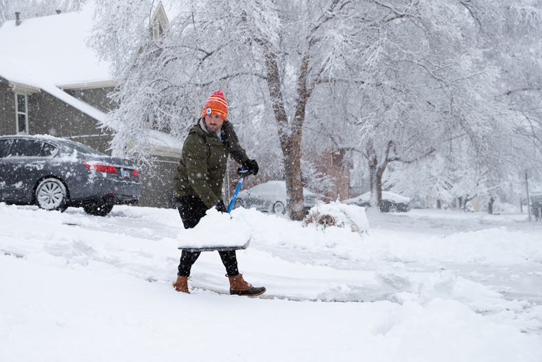 Kyle Cook shovels his driveway as well as his neighbor's on Tuesday morning as snow continues to fall in Overland Park.