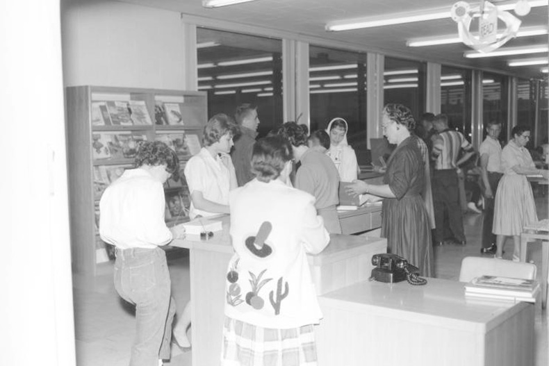 Patrons appear to line up around the librarian’s desk at the Antioch Library around 1957. Photo via JoCo History. 