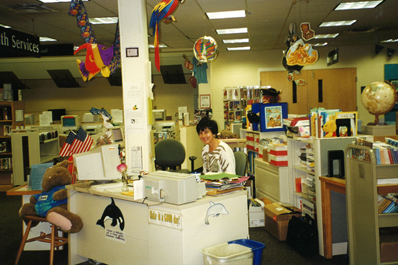 A librarian smiling at the Antioch Library’s youth services desk in summer of 1999. Photo courtesy Johnson County Library. 