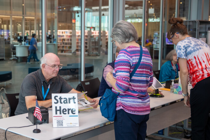 Election Official Don Grundy checks in a voter at Olathe Indian Creek Library on Tuesday, August 6.