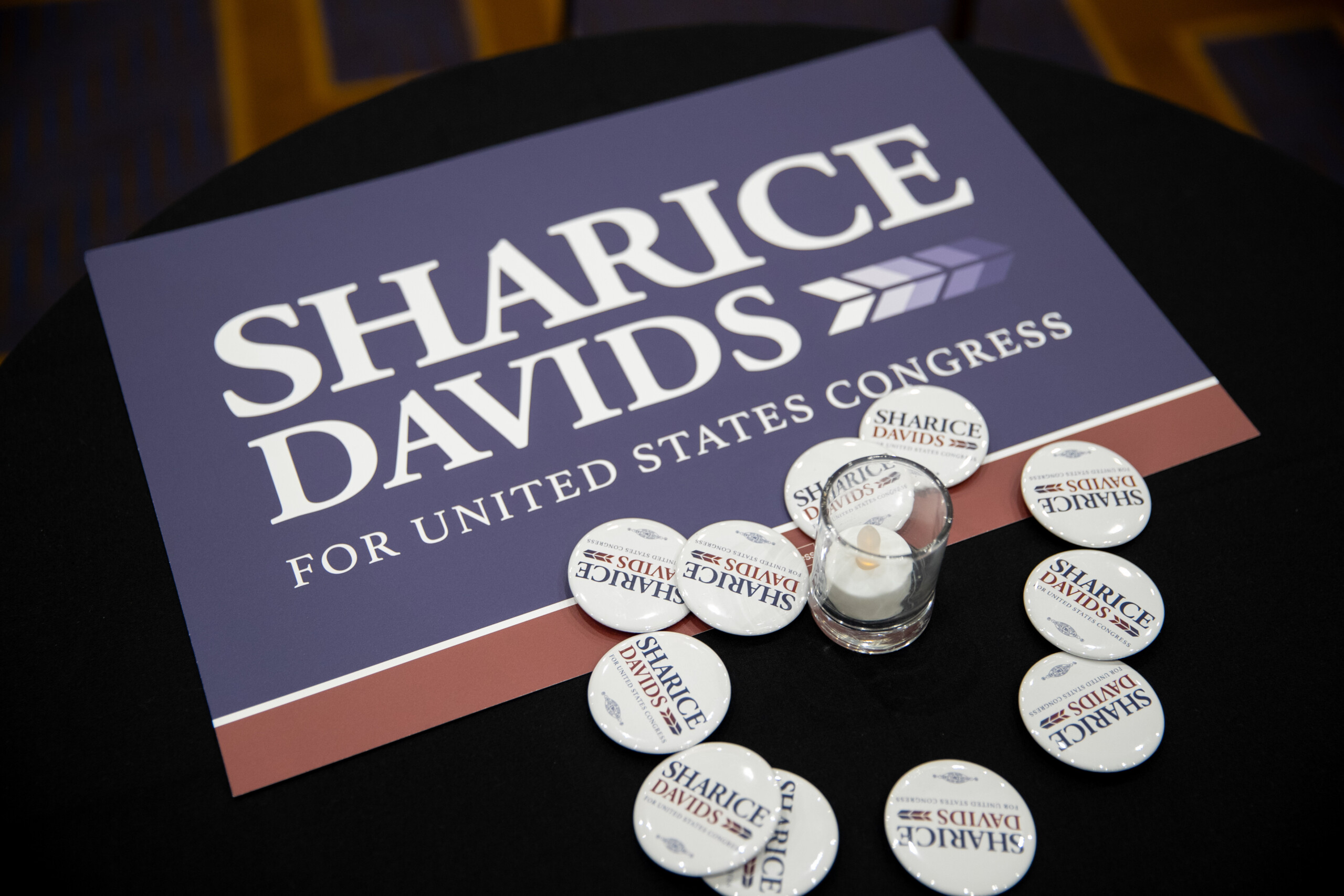 Signs and buttons for Sharice Davids cover the tables at the Johnson County Democratic Party's watch party.
