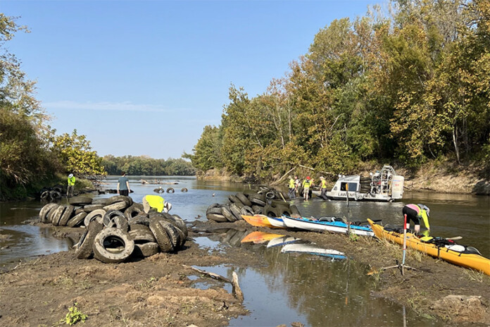 Friends of the Kaw’s trained volunteers pull tires out of the Kansas River between Eudora and De Soto in October. A Kansas Department of Wildlife and Parks game warden helps ferry the tires away by boat.