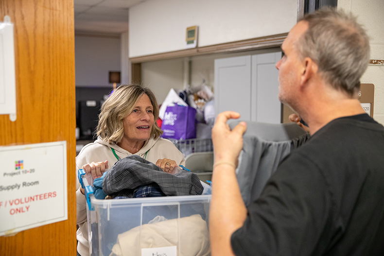 Project 1020 volunteer Kathleen Osbern (left) helps William Coleman, one of the shelter guests, pick out a new pair of shorts.