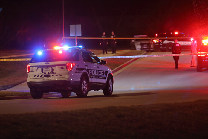 Overland Park Police officers and vehicles near the taped-off crime scene. The Take 5 Oil Change building is out of frame to the right.