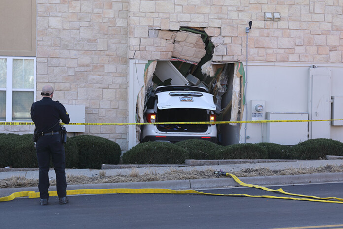 An Overland Park Police supervisor takes photos of the SUV and damaged building after the driver was taken away by ambulance.