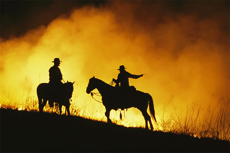 Riders patrol the edge of a raging grass fire on the prairie. Photographer Jim Richardson captured the drama of the annual ritual in the Flint Hills.