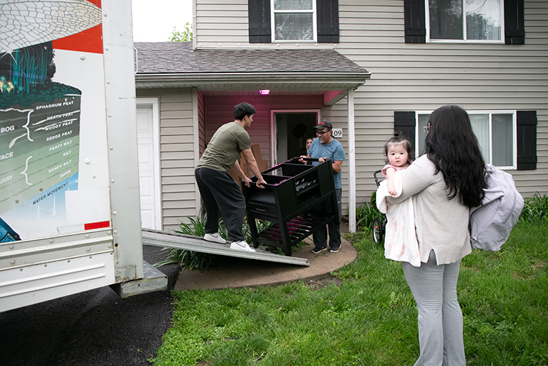 A young man and his father pack their belongings into a moving truck while the man’s wife and infant daughter look on. The young couple had just moved into Aspen Place last Thursday and have been forced to move again. For now, the intergenerational family will stick together under one roof somewhere else.