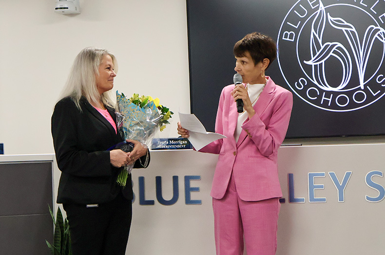 Blue Valley Superintendent Tonya Merrigan (right) presents flowers to Kristi McNerlin in honor of her Distinguished Service Award. McNerlin is moving her career to the Raymore-Peculiar School District.