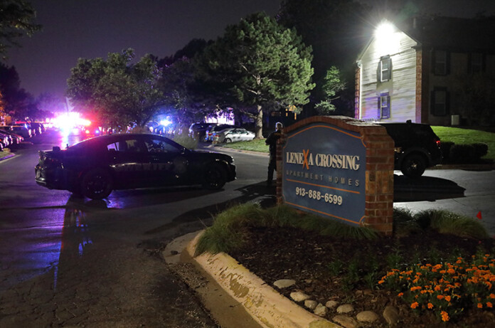 Two Johnson County Sheriff's deputies block the east entrance to the apartment complex, off of Monrovia Street, with the crime scene in the distance.