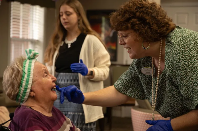 Amanda McNish dabs lipstick on a smiling Sandy. McNish is the connections care coordinator at Pegasus Landing, responsible for organizing programming to engage residents in enjoyable activities like Gorgeous Grandmas Day.