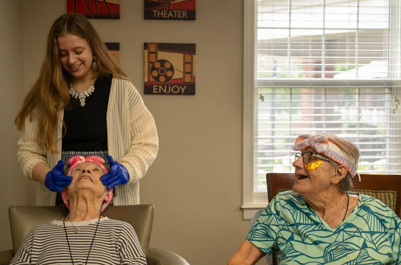 Cheyenne McNish applies lotion on Charlotte while fellow resident and friend Jenny watches on. Amanda and Cheyenne are a mother-and-daughter pair who bond through their work and the connections they make with residents.