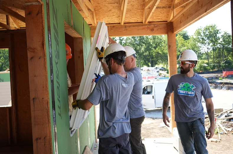 A group from Foundation Recovery Systems helps place a front-facing window in one of the single-family homes a part of an affordable housing project through Habitat for Humanity.