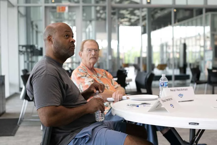 Two men sit at a table at the Olathe Public Library as part of a focus group. They're talking to a moderator who is off screen.