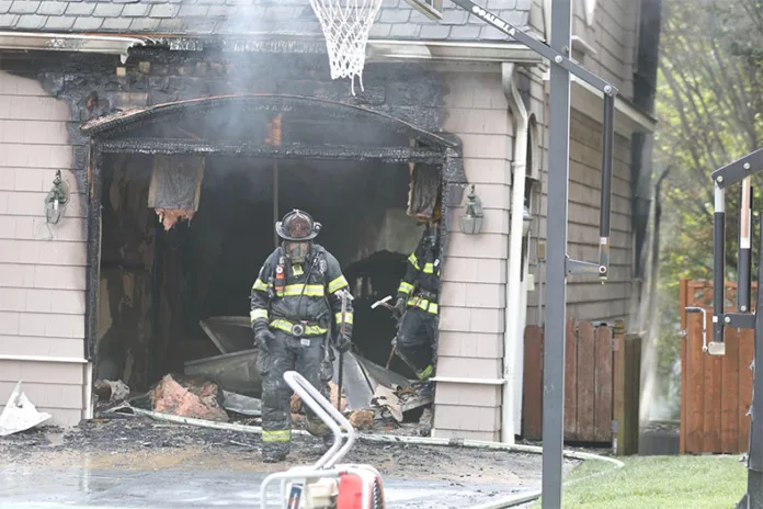 A firefighter stands outside the burned-out garage of a Fairway home following a fire caused by a lithium-ion battery failure on Monday, July 28.