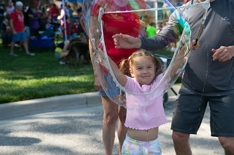 A young girl creates a large bubble at VillageFest 2025.