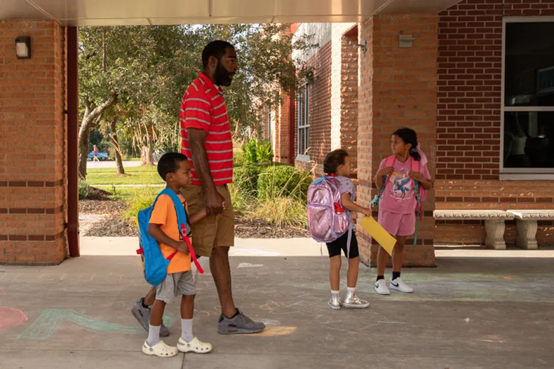 A parent walks his son into Bentwood Elementary School as other students prepare to head inside.