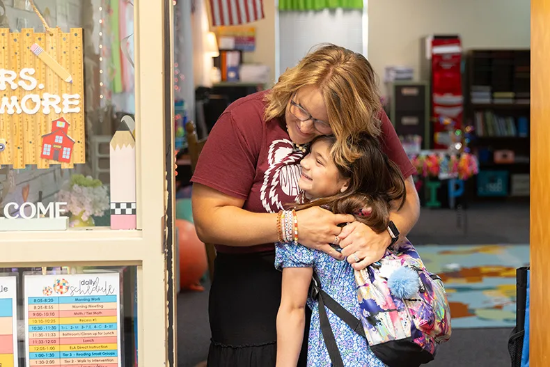 Third-grade teacher Melanie Gilmore hugs a student on the first day of school at Madison Elementary.