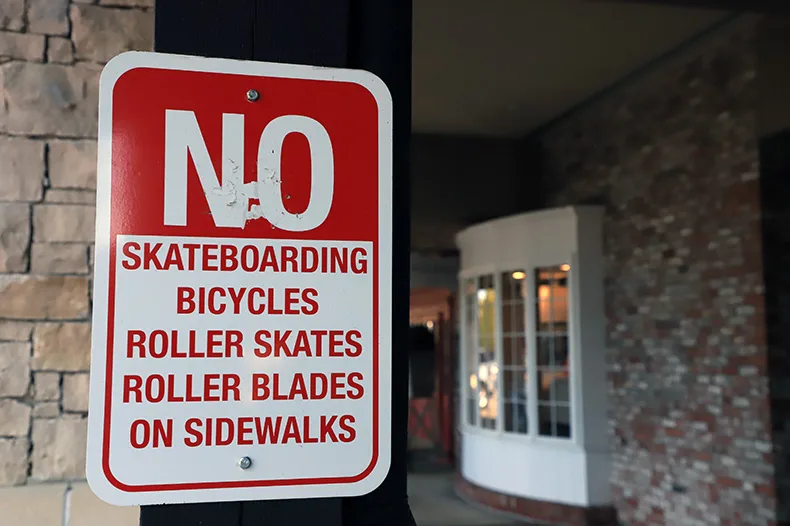 A sign informing shoppers at the Ranch Mart shopping center that skateboards and bikes are prohibited on the sidewalks. Now, e-bikes and e-scooters are also banned.