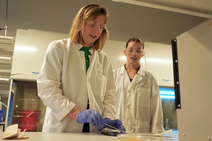 During her visit, Olympian Katie Ledecky (left) collects a sample for analysis alongside De Soto High senior Abby Wagoner.