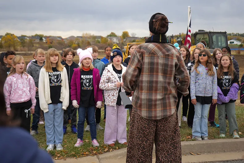 Music teacher Natasha Singer leads Madison Elementary School students during their musical performance to celebrate the start of construction on a new elementary school in Gardner.