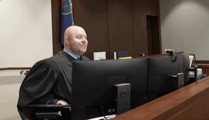 A judge sits behind a computer.
