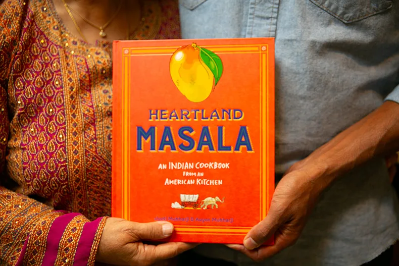 The mother-son duo hold a copy of "Heartland Masala." Photo credit Juliana Garcia.