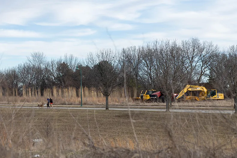 Two women walk their dogs past construction equipment on West 137th Street near the intersection of Mission Road on Wednesday, Feb. 18, in Leawood.