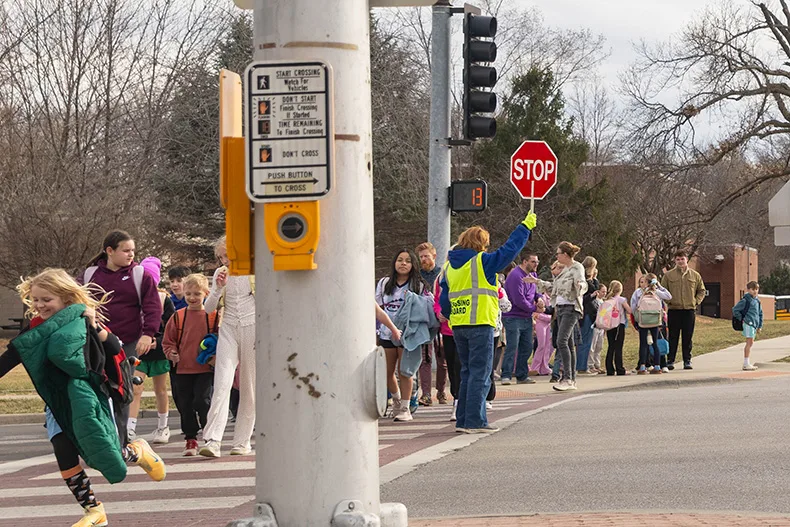 A crossing guard helps children from Corinth Elementary School cross the intersection of 83rd Street and Mission Road after school on Tuesday, Feb. 24.