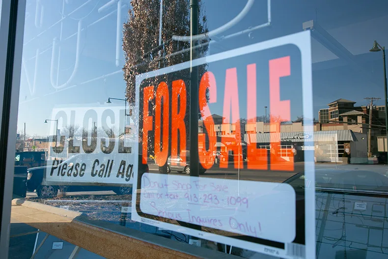 A "for sale" sign hangs in the front door of Holy Moly Doughnuts, which took over the Fluffy Fresh Donuts space in November.