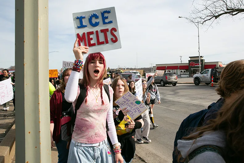 A student marches along Johnson Drive holding a sign that reads "ICE melts." Photo credit Juliana Garcia. 