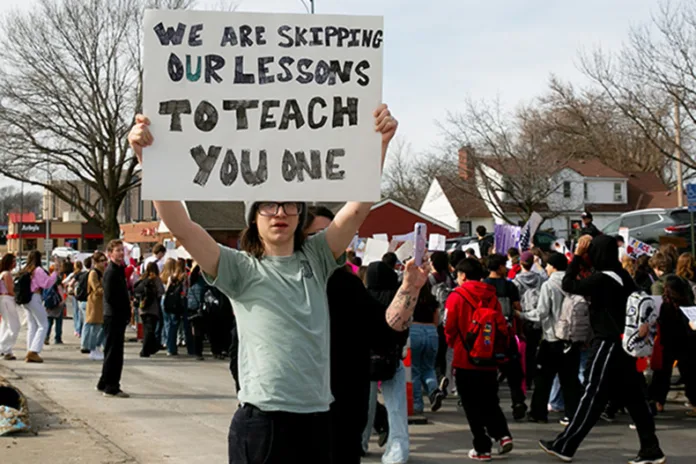 A student holds up a sign that reads 