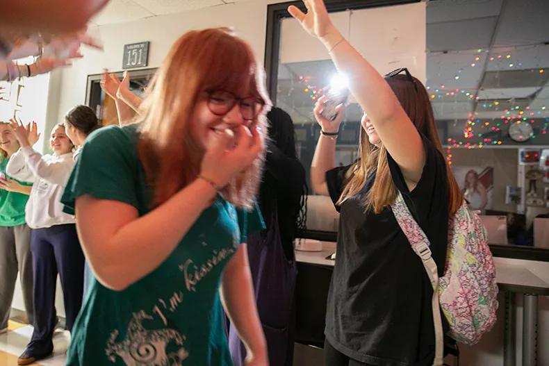 Sofia Ball walk through a hand tunnel of fellow student journalists after being named the Kansas High School Journalist of the Year. Photo credit Juliana Garcia.