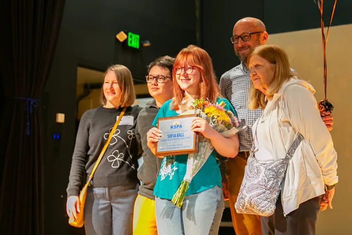 Sofia Ball, center, stands with her family in The Little Theater at Shawnee Mission Northwest after receiving the Susan Massy Award, named after Ball's former journalism adviser.