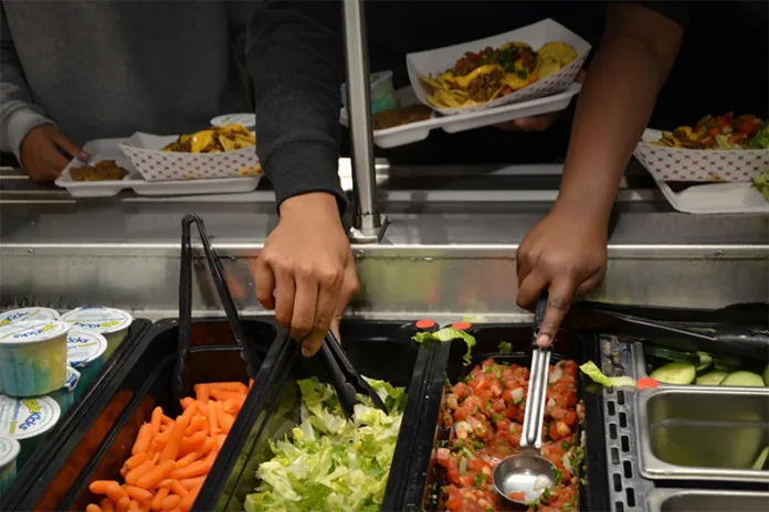 Students at Rosedale Middle School in Kansas City, Kansas, serve themselves local produce on their lunch tray.