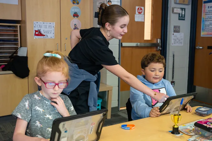ASanta Fe Trail Middle School student helps Washington Elementary students with their devices.