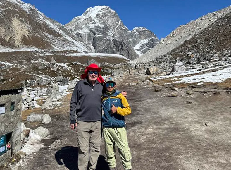 Two men in front of a mountain.