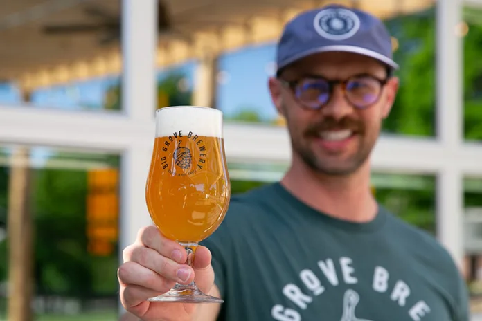 Tyler Carter, the taproom marketing manager at the Big Grove in Prairie Village, holds a Royal Eddy, an imperial IPA brewed by Big Grove's patio. Photo credit Juliana Garcia.