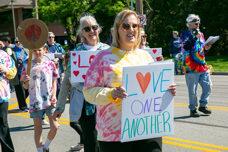 People for PV walked down Mission Road under a 1960s theme, one holding a sign that reads "love one another." Photo credit Juliana Garcia. 
