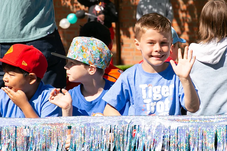 A Tomahawk student waves to the crowd lining Mission Road on Saturday morning. Photo credit Juliana Garcia. 