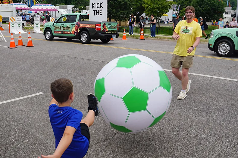 A kid kicks at ball at the Old Shawnee Days Parade. Photo credit Andrew Gaug.