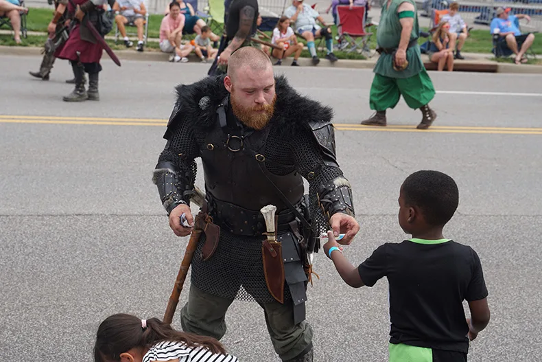 A KC Renaissance Festival performer hands out coupons at the Old Shawnee Days Festival. Photo credit Andrew Gaug.