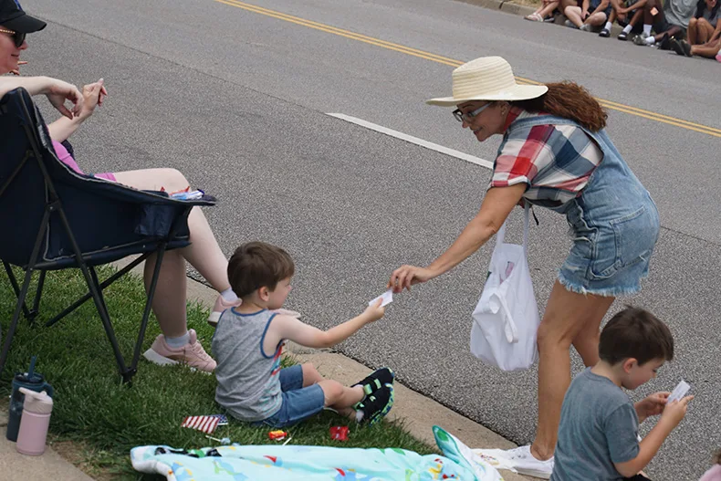 A kid takes seeds at the Old Shawnee Days Parade. Photo credit Andrew Gaug.