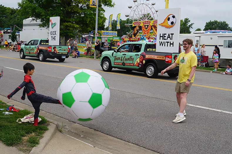 A kid in a Spider-Man costume kicks a giant ball at the Old Shawnee Days Parade. Photo credit Andrew Gaug.